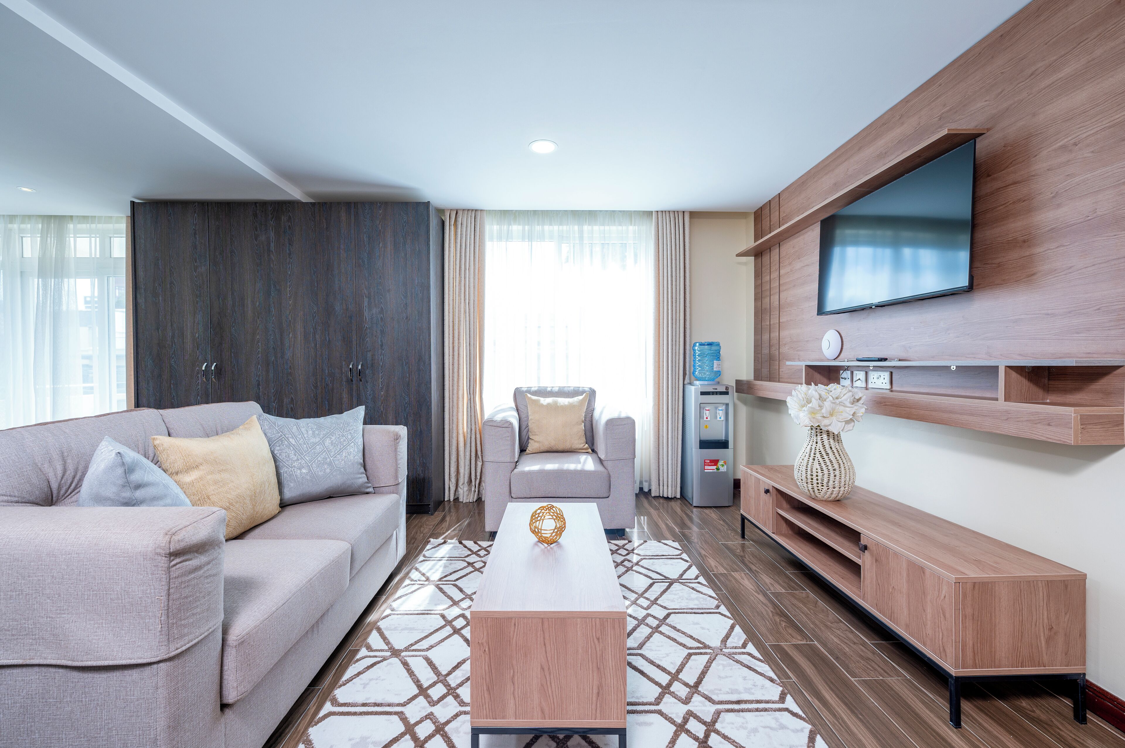 A modern living room with a sofa, armchair, coffee table, TV, and built-in entertainment unit.
