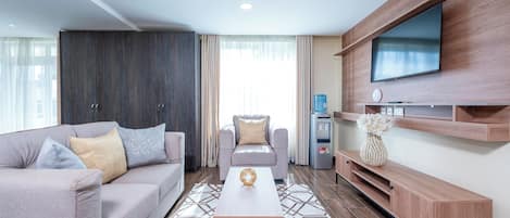 A modern living room with a sofa, armchair, coffee table, TV, and built-in entertainment unit.