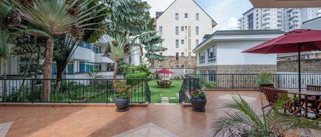 A courtyard with a view of a building, outdoor seating, and potted plants.