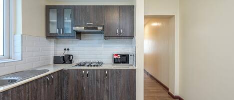 A modern kitchen with dark wood cabinets, white subway tiles, and stainless steel appliances.