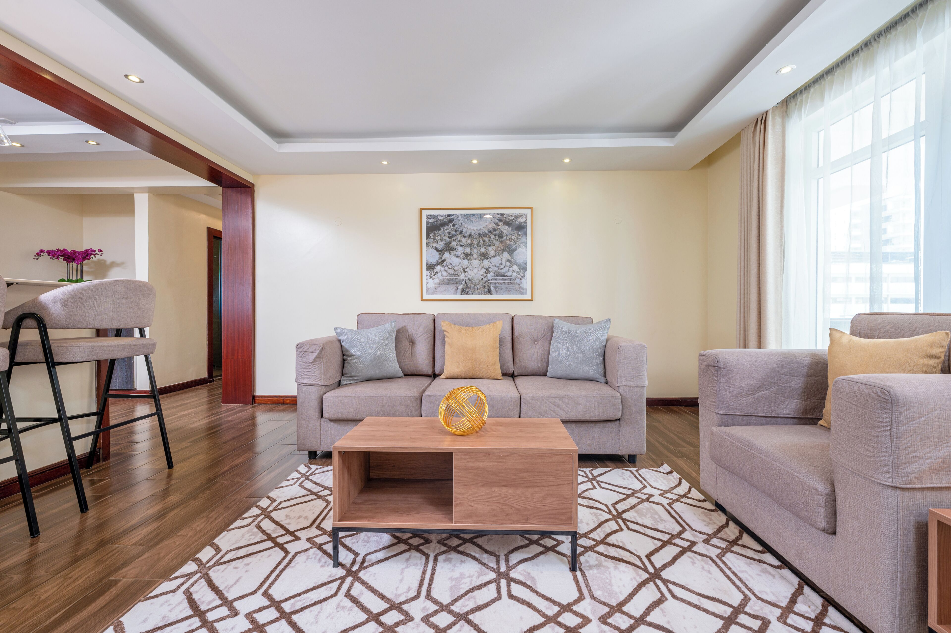A modern living room with a sofa, two armchairs, a coffee table, and a patterned rug.
