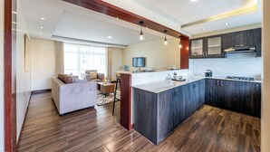 A modern kitchen with a central island, dark wood cabinetry, and a dining area with a sofa and chairs. - Roma Courts Serviced Apartments (Nairobi)