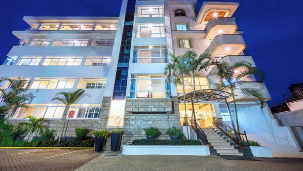 A multi-story hotel with a modern design, featuring a central staircase, balconies, and a well-lit facade. - Roma Courts Serviced Apartments (Nairobi)