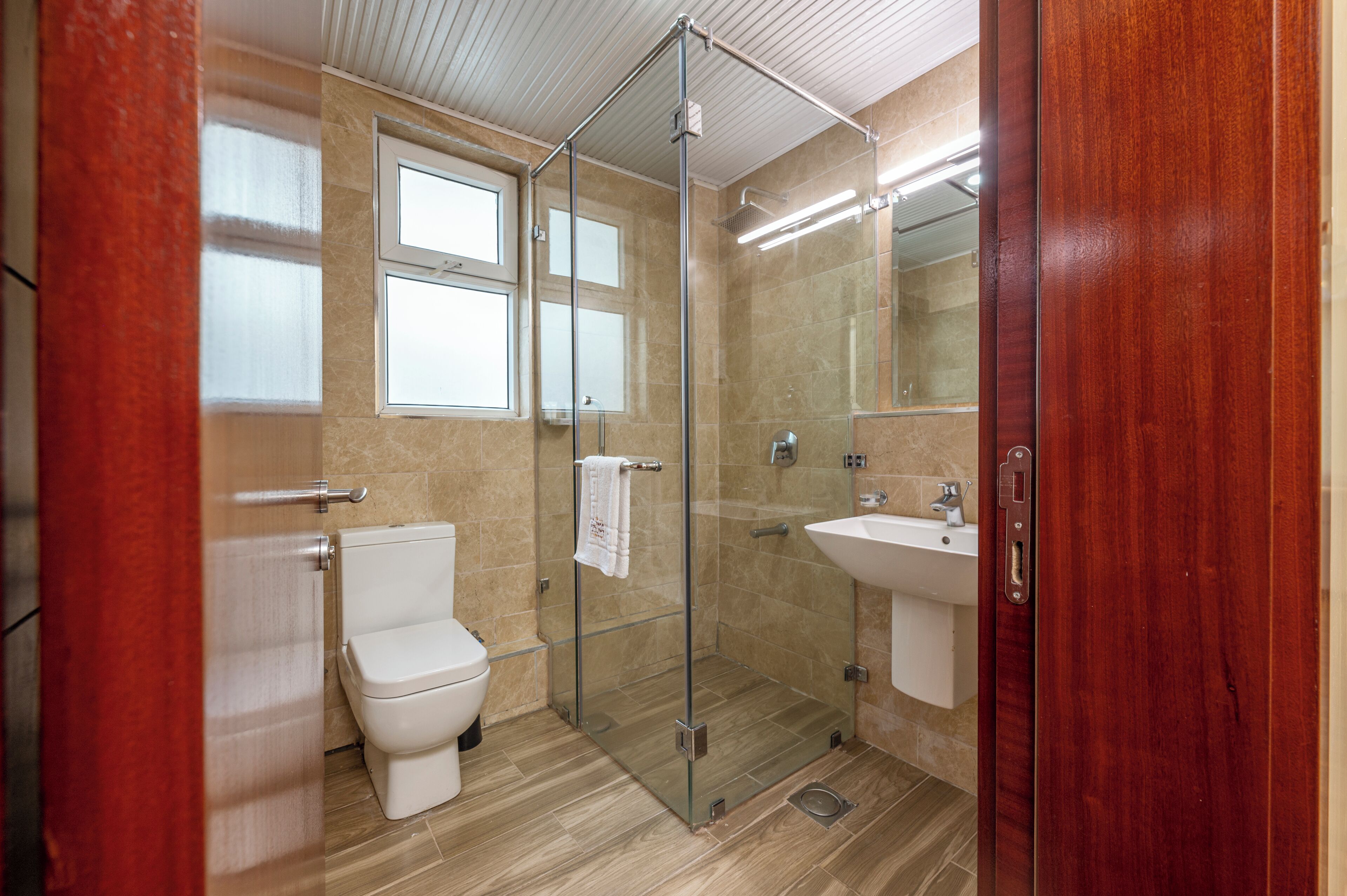 A modern bathroom with a glass shower enclosure, a toilet, and a sink.