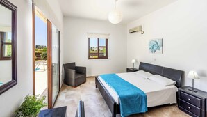 A bedroom with a bed, bedside tables, a chair, a window, and a view of the outside. - Villa Anthia (Pegeia)