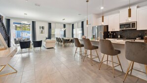 A modern kitchen with white cabinets, stainless steel appliances, and pendant lighting.
