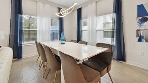 A modern dining area with a white table, brown chairs, and a blue vase.