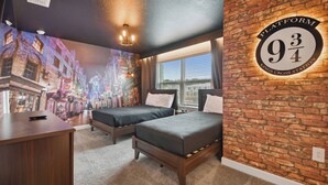 A hotel room with two beds, a brick accent wall, a mural of a city street, and a sign indicating the room number.