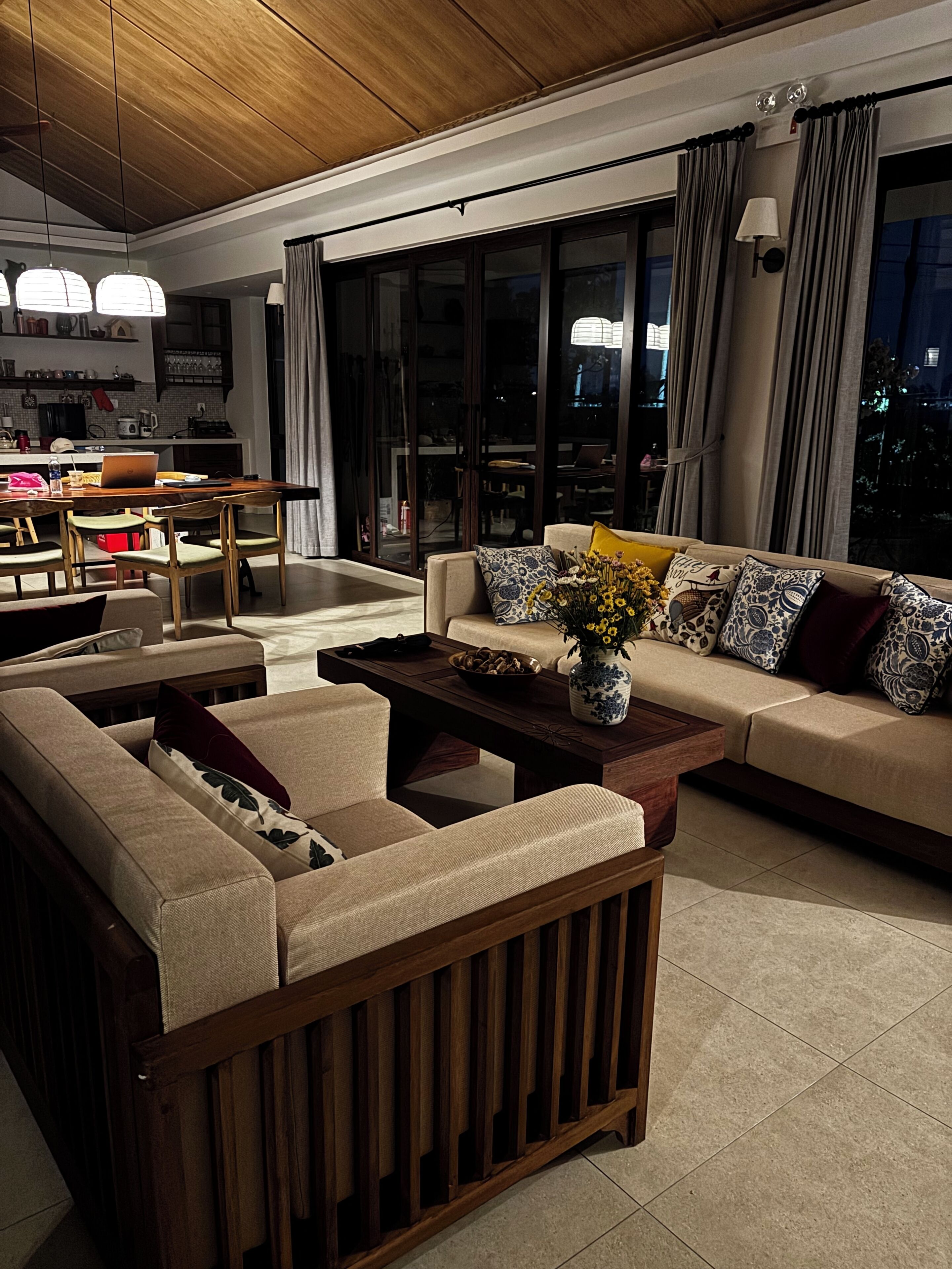 A modern living room with a sofa set, a wooden coffee table, and a dining area with a table and chairs.