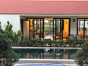 Zona junto a la piscina con techo de baldosas, mobiliario exterior y vistas del paisaje circundante.