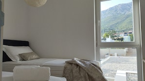 A bedroom with a bed, pillows, a blanket, and a view of a mountainous landscape through a window. - Villa With Panoramic Views on the Sea, Islands, City and Hill (Kaštel Sućurac)