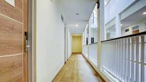 Un pasillo largo y estrecho con suelo de madera y paredes blancas.