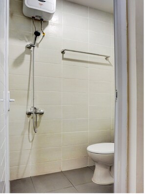A small, clean bathroom with white tiles, a toilet, a shower with a handheld showerhead, and a towel rack.