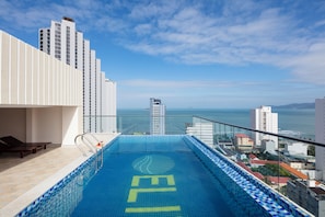 Une piscine sur le toit offrant une vue sur l’océan et le paysage urbain.