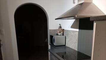 A kitchen with a tiled floor, a microwave, and a stainless steel range hood.