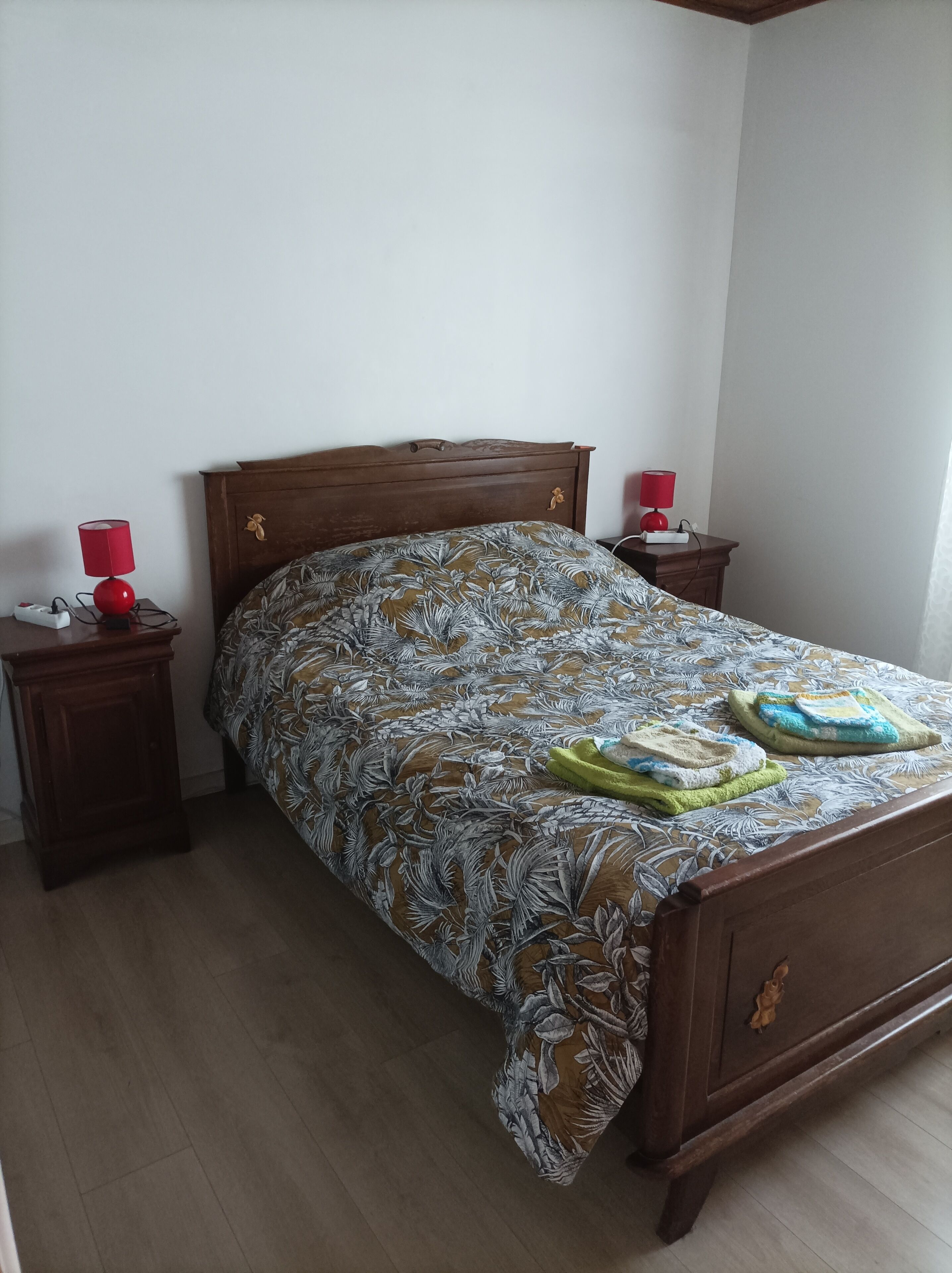 A bedroom with a wooden bed, two bedside tables with lamps, and a floral bedspread.