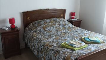A bedroom with a wooden bed, two bedside tables with lamps, and a floral bedspread.