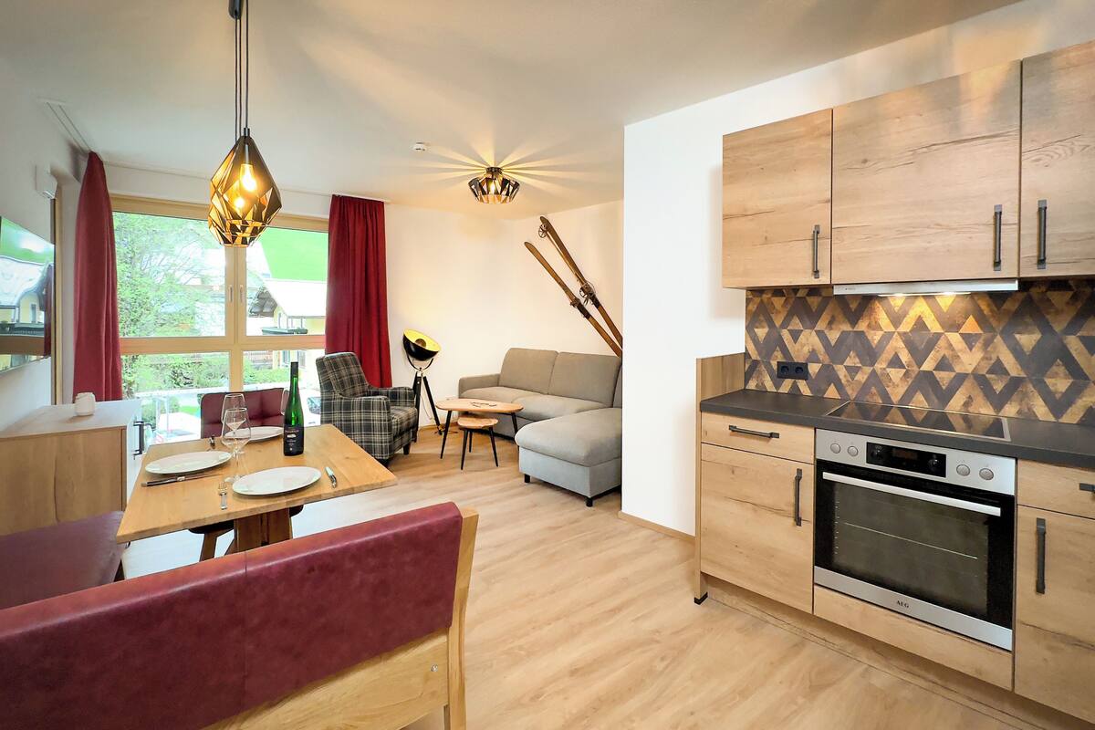 A modern kitchen with wooden cabinets, a built-in oven, and a dining area with a table and chairs.