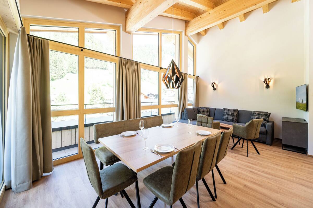 A dining area with a wooden table, chairs, and a sofa.
