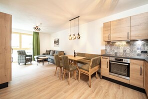 Eine moderne Küche mit Holzausstattung, einem eingebauten Ofen und einem Essbereich mit Tisch und Stühlen.