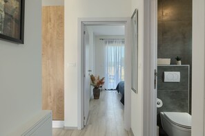 A hallway leading to a bedroom with a bed, a potted plant, and a bathroom with a toilet and a towel rack. - House Bronzin by Istra Vacation (Kanfanar)