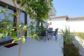 An outdoor patio with a table and chairs, surrounded by greenery and a white building with a tiled roof. - House Bronzin by Istra Vacation (Kanfanar)