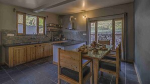 Una cocina moderna con una isla central, armarios de madera y un comedor con mesa y sillas.