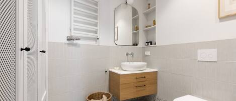 Une salle de bain moderne avec un lavabo blanc, un meuble-lavabo en bois et des toilettes blanches.