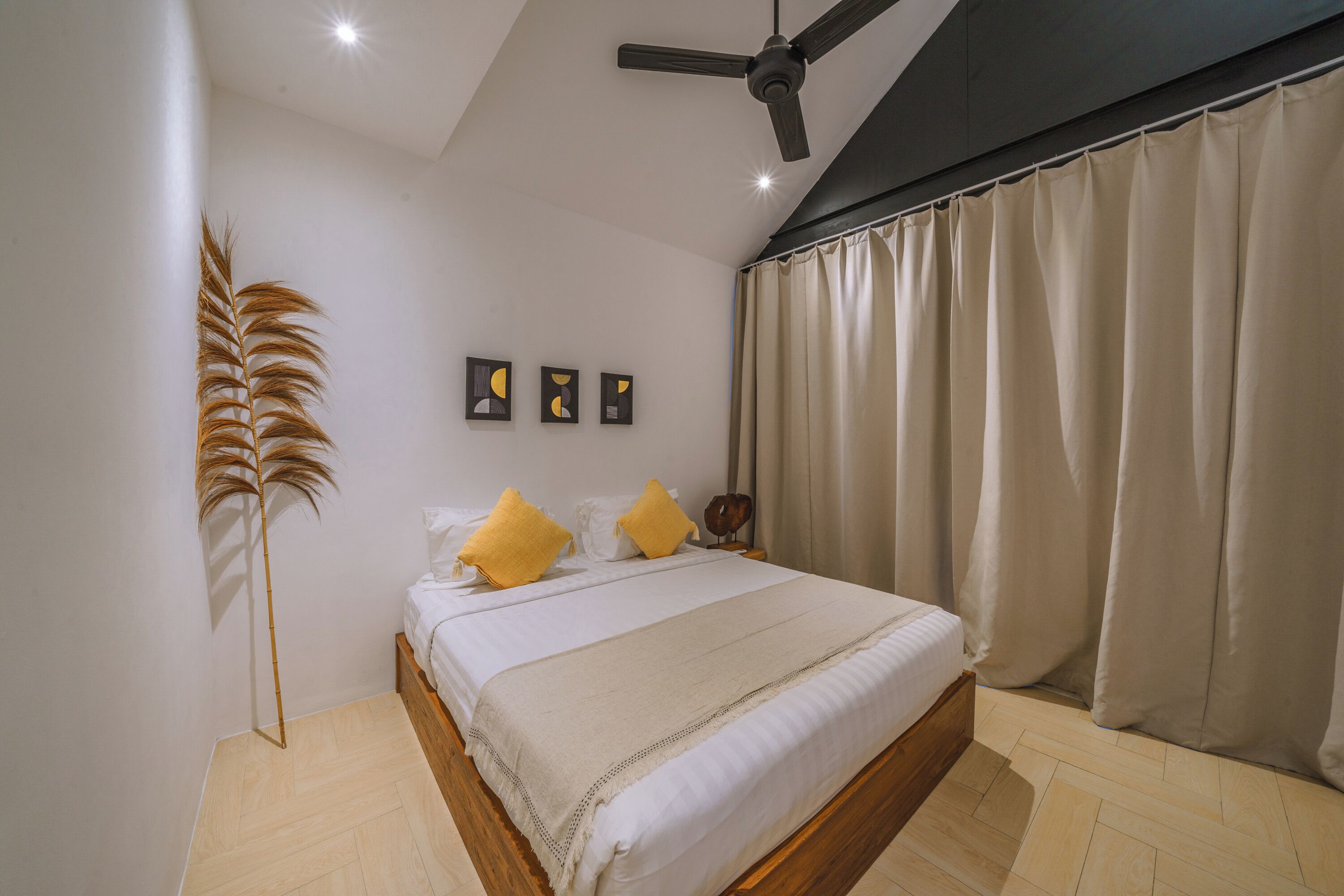 A bedroom with a bed, a ceiling fan, a floor lamp, and a window with curtains.