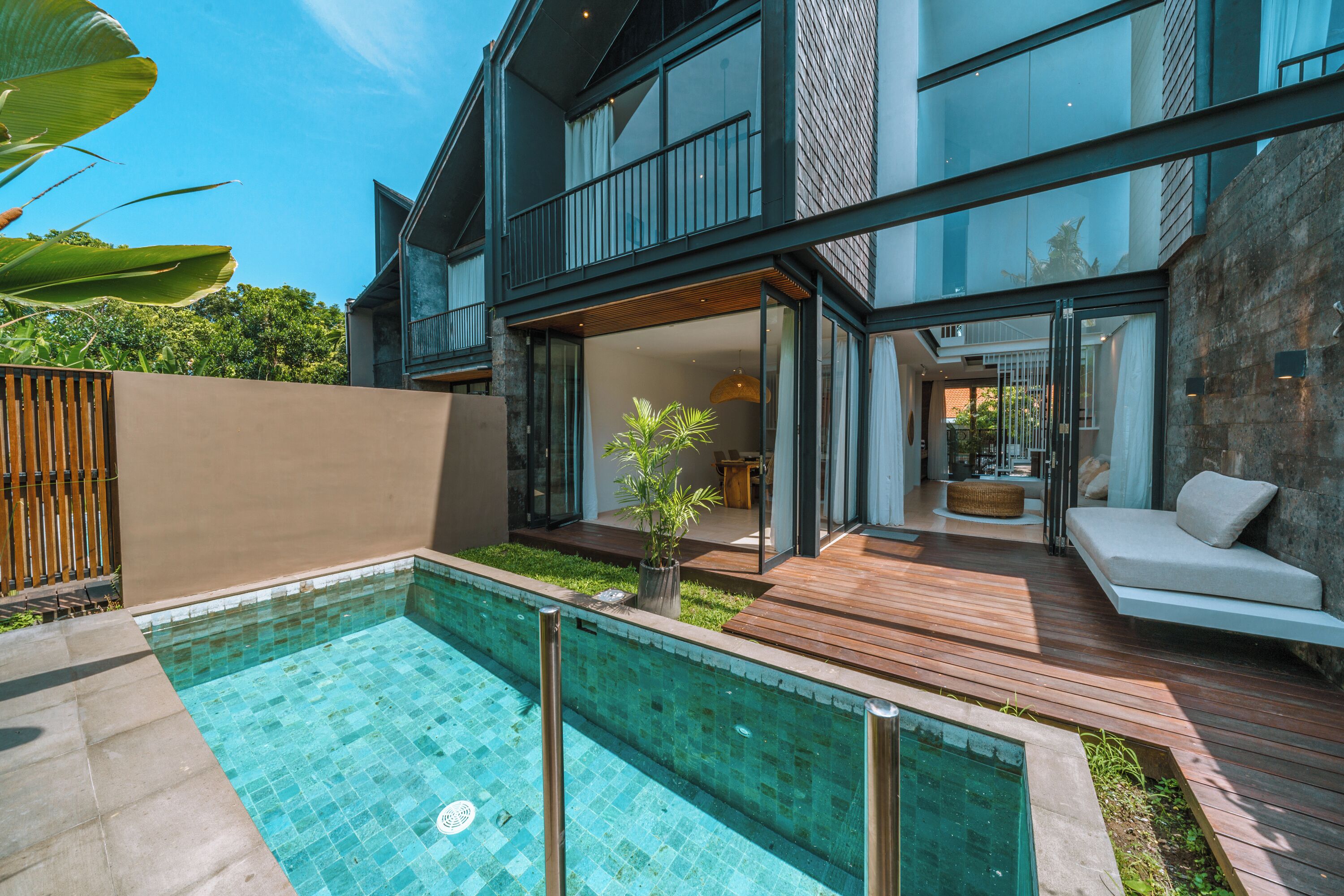 A modern house with a swimming pool, wooden deck, and a glass-enclosed patio.