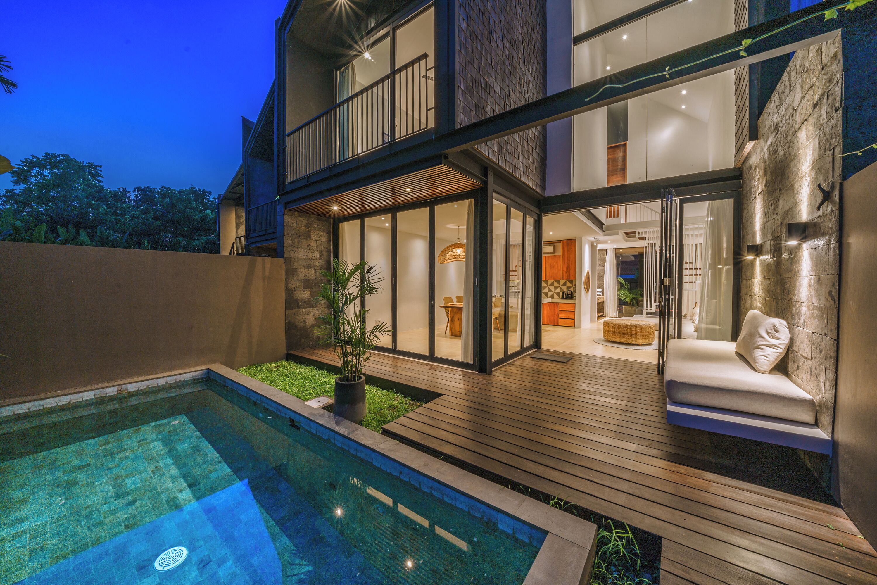 A modern house with a swimming pool, a wooden deck, and a glass-enclosed patio area.