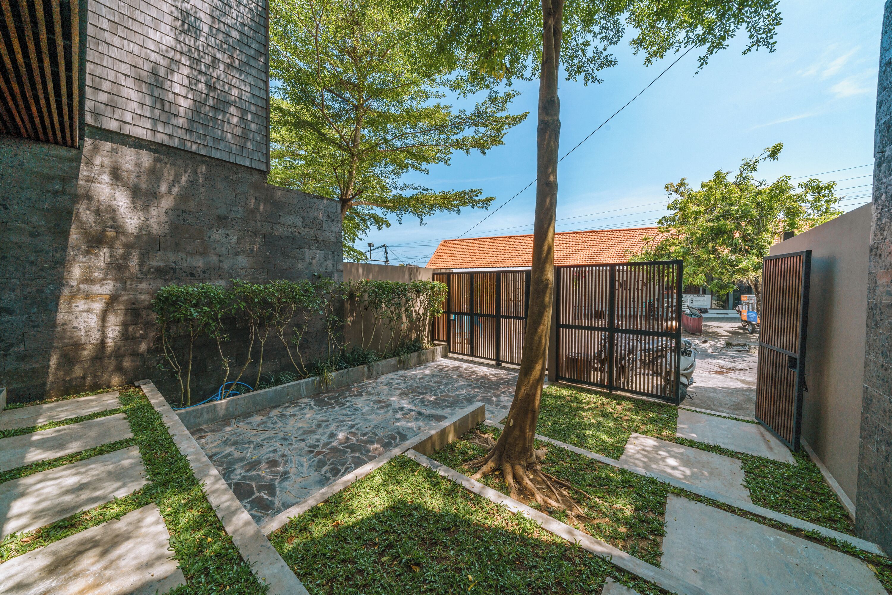 Un patio con un sendero de piedra, un árbol y una entrada con portón.