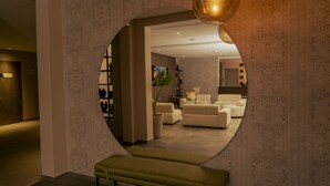 Ein runder Spiegel spiegelt ein modernes Wohnzimmer mit Sofas, einer Pflanze und einer Bank.