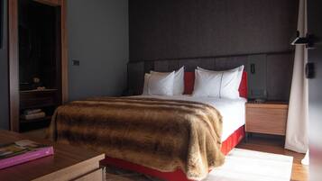 Ein modernes Hotelzimmer mit einem großen Bett, Holzboden und einem eingebauten Kleiderschrank.