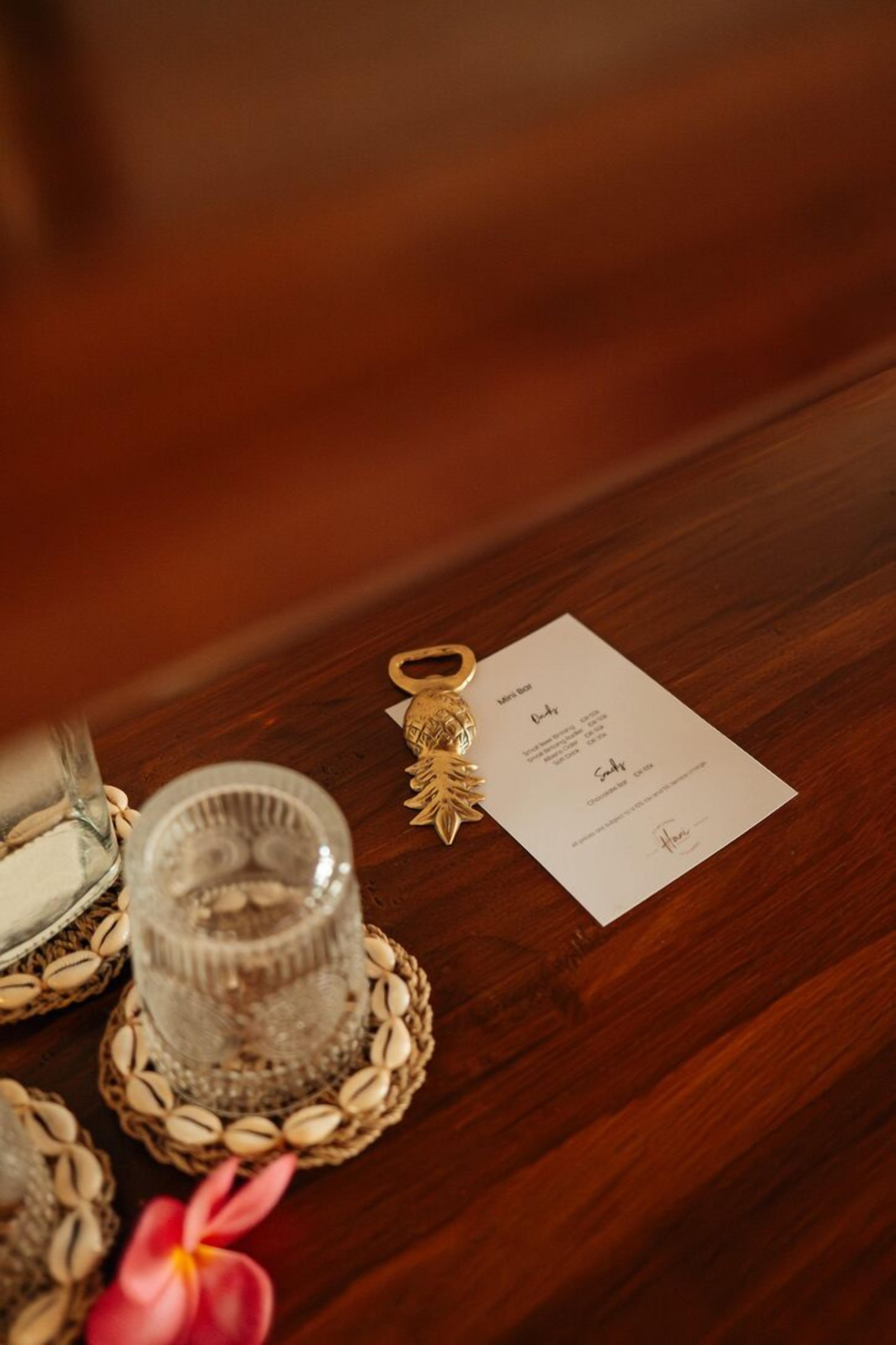 A wooden table with a glass candle holder, a small card, and a decorative keychain.