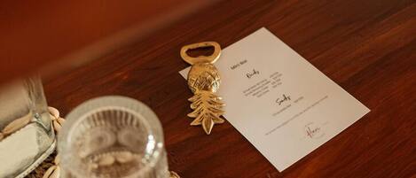 A wooden table with a glass candle holder, a small card, and a decorative keychain.