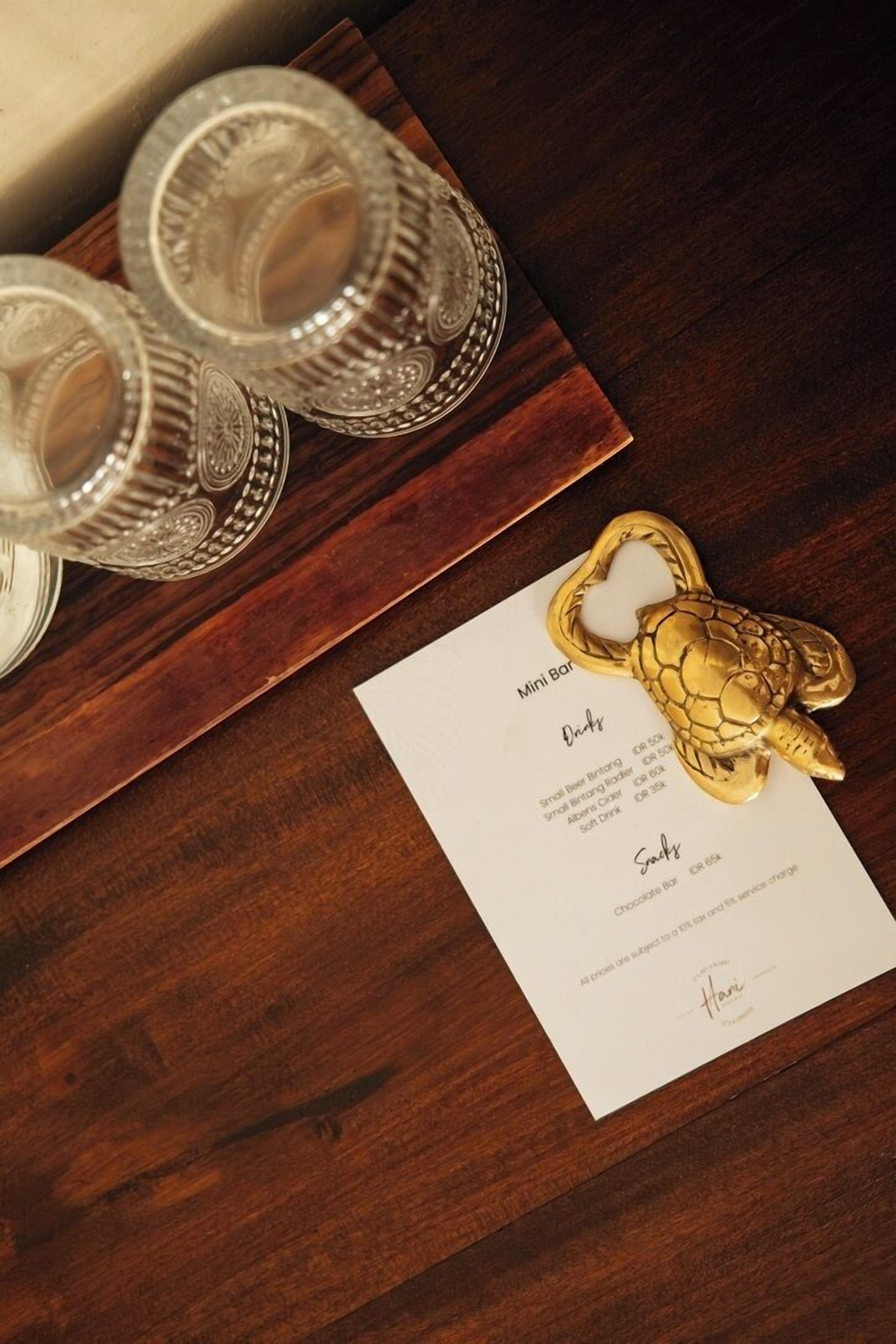 Une table en bois, sur laquelle se trouve un menu et un porte-clés en forme de tortue dorée.