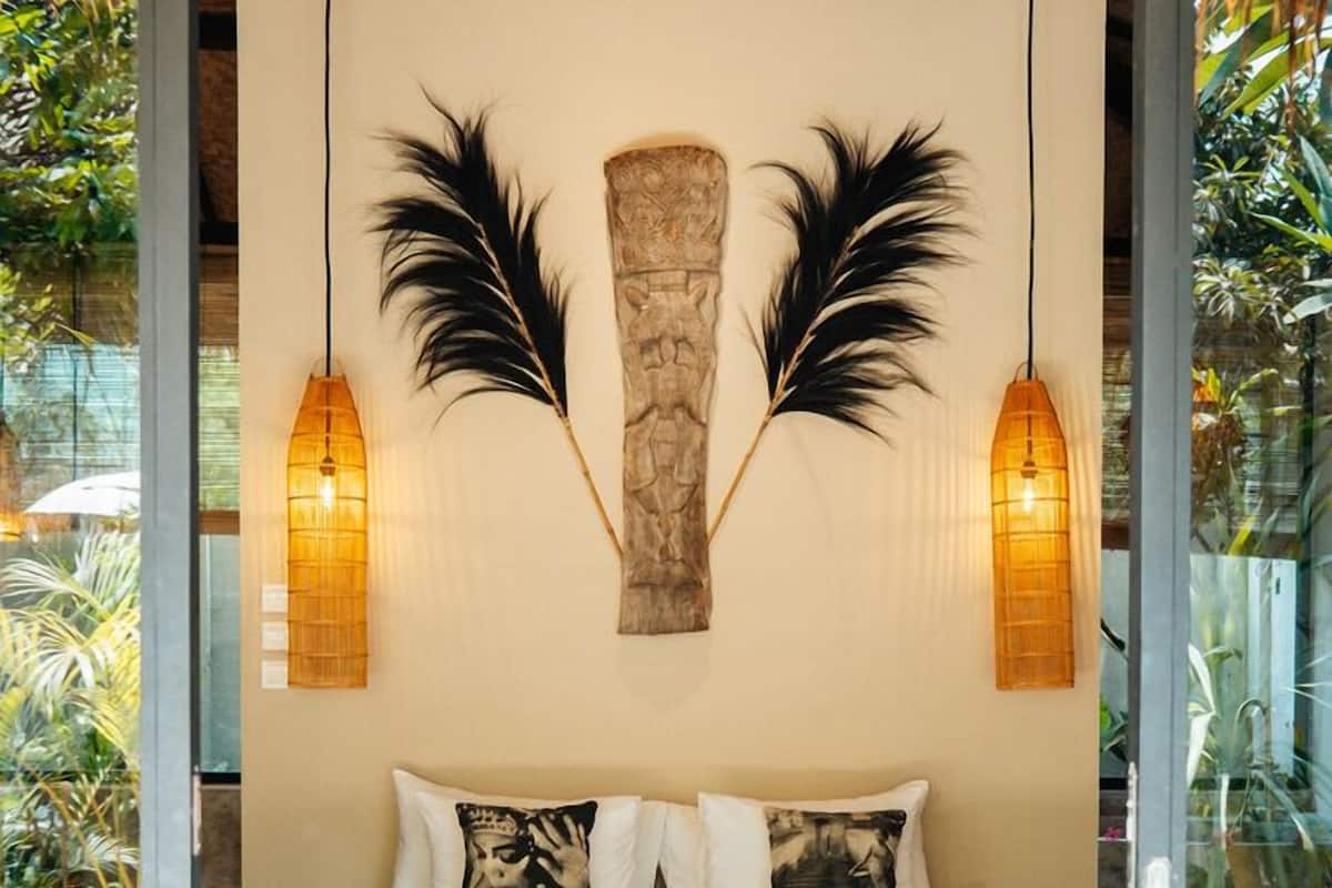 A bedroom with a bed, decorative wall art, and two wall-mounted lamps.