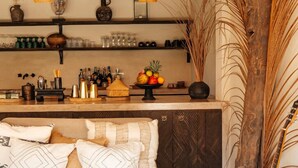 A cozy living room with a sofa, a coffee table, and a guitar. There is a wooden ceiling and a shelf with various items. - Hani Hideaway (Gili Air)