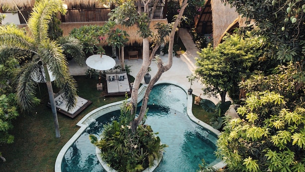 A circular pool with a central island, surrounded by lush greenery and a thatched-roof structure. - Hani Hideaway (Gili Air)