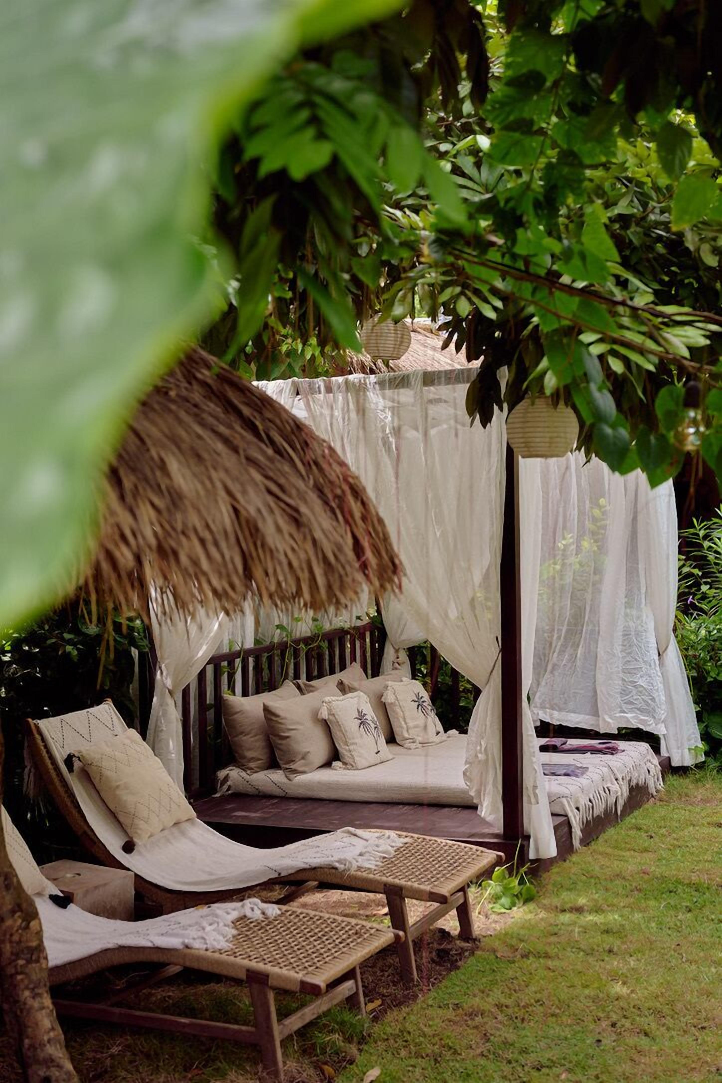 A cozy outdoor seating area with a canopy, cushioned chairs, and a bench.