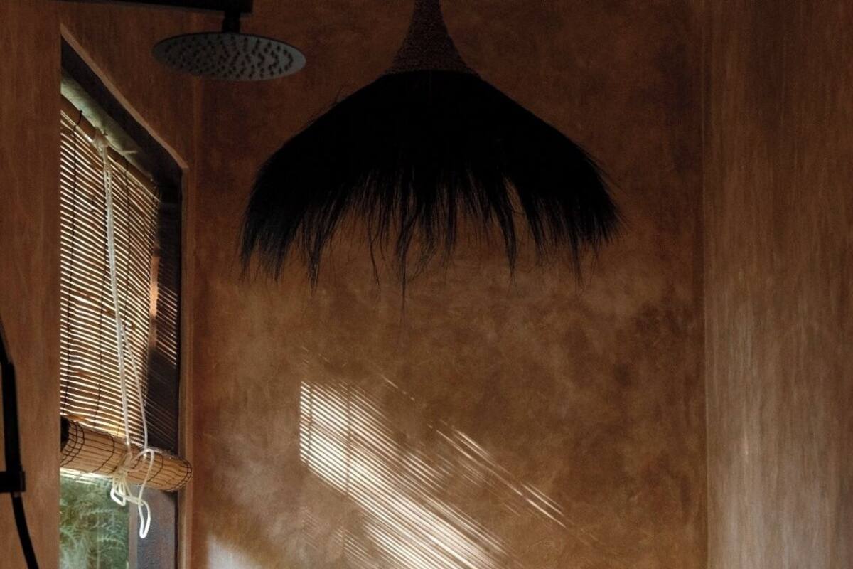 A bathroom with a large window, a black pendant light, and a bathtub.