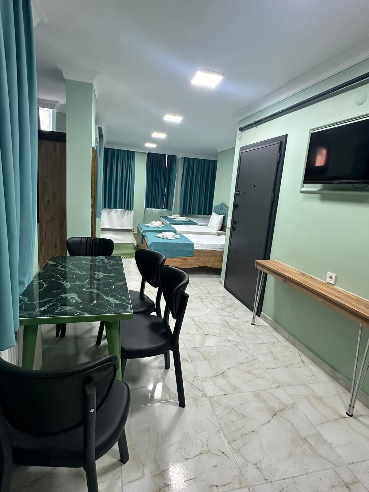 Une chambre d’hôtel équipée d’une table à manger, de chaises, d’un lit, d’une télévision et d’un petit bureau.