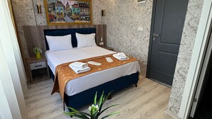 Ein modernes Hotelzimmer mit einem großen Bett, einem kleinen Tisch mit einer Pflanze und einer Tür.