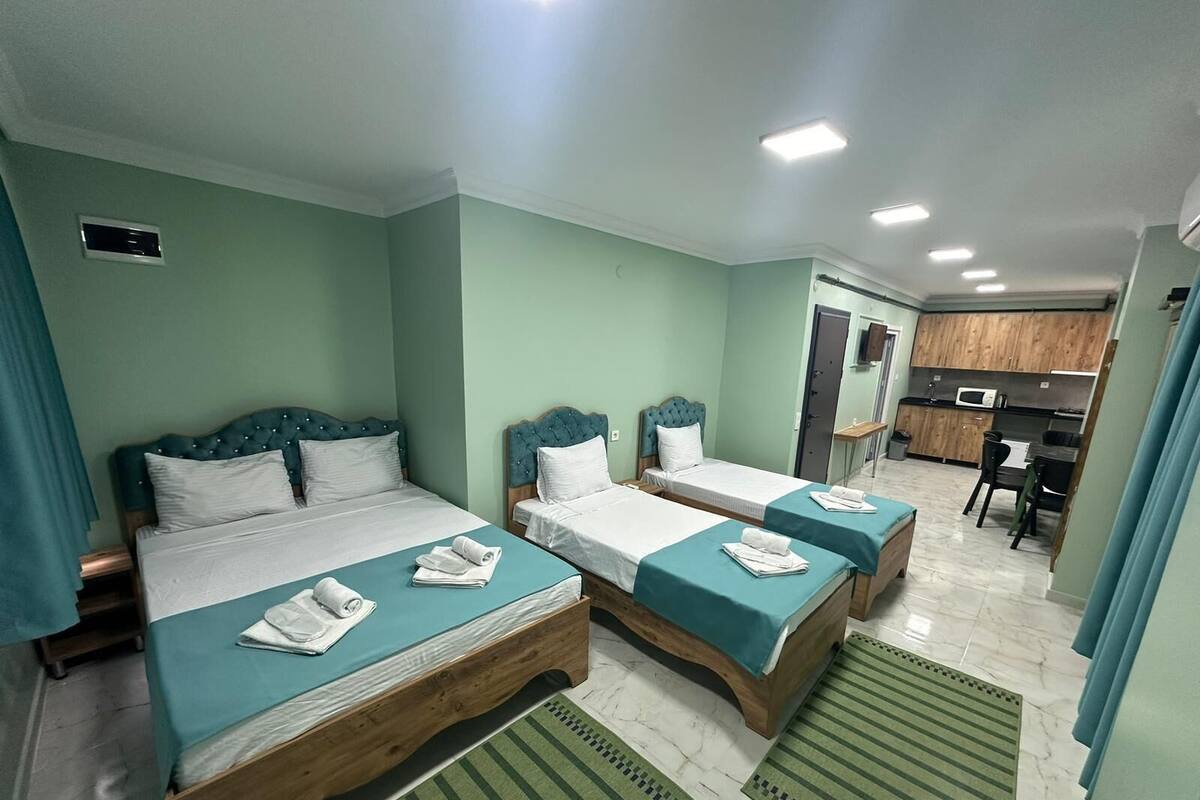 Una habitación de hotel con dos camas, kitchenette y baño.