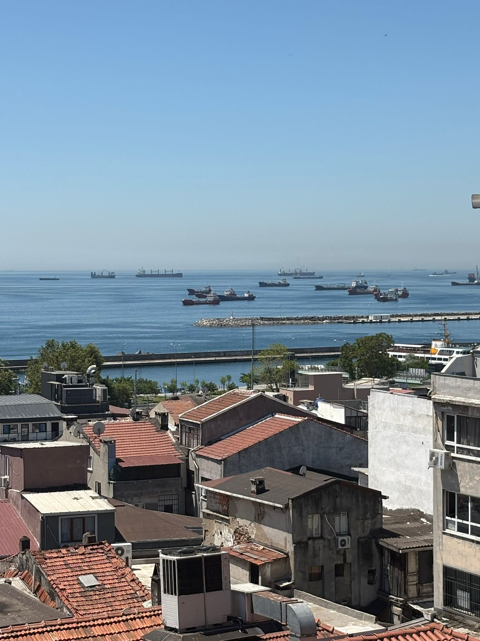 A coastal cityscape with a view of the sea and several ships.