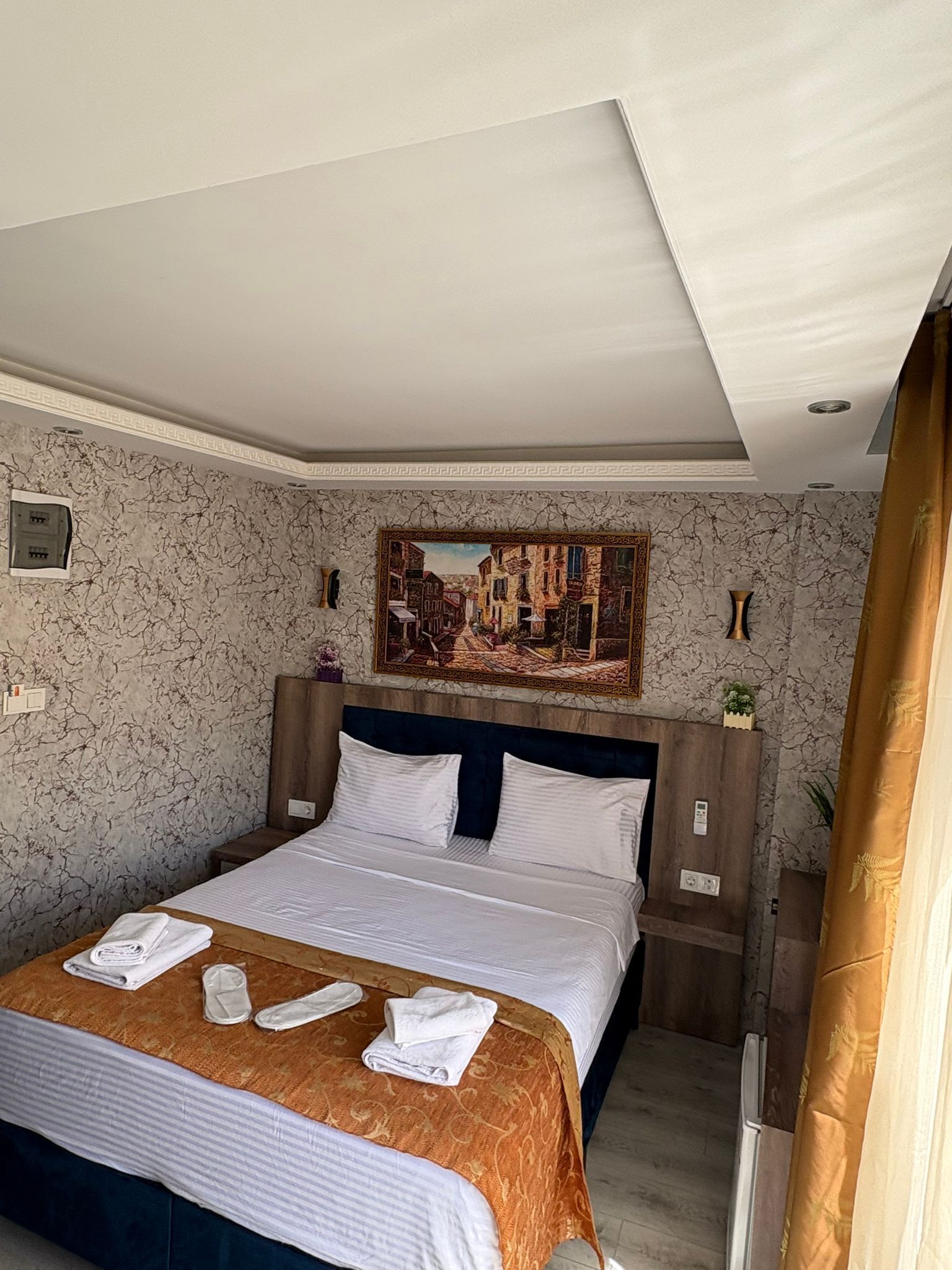 Une chambre d’hôtel avec un lit, un tableau au mur et une fenêtre avec des rideaux.