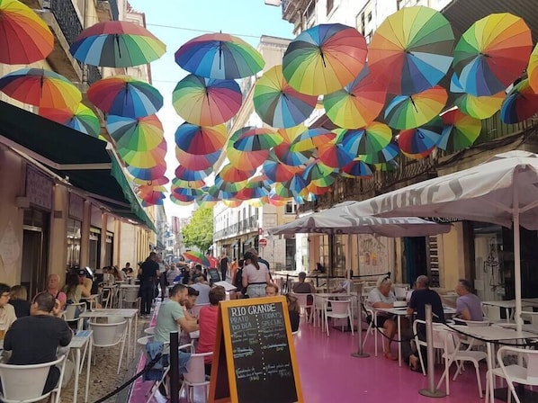 A street with outdoor seating and colorful umbrellas.