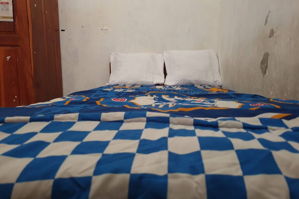 A bed with a blue and white checkered bedspread and two white pillows.