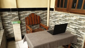 A small room with a tiled floor, a wooden chair, a table with a laptop, and a tiled wall with a black and white pattern. - OYO Life  92620 Syfa Kost (Malang)